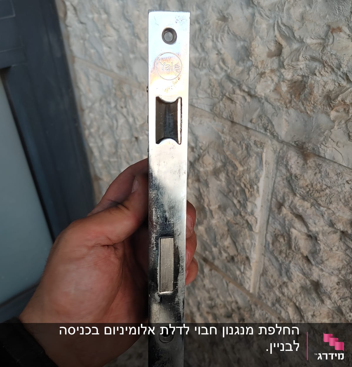 יד מחזיקה מנעול מתכת על רקע קיר אבן